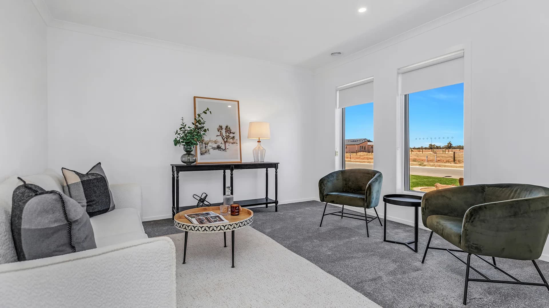 Living room with a pale sofa, dark green armchairs and a black console under framed artwork at Altesse Avenue, Moama