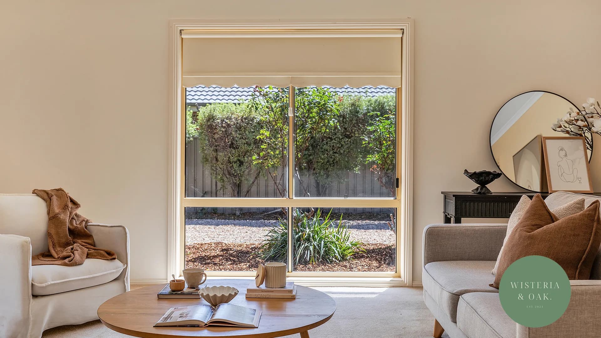 Living room with a pale armchair, round coffee table and a window to the garden at Caroline Court, Echuca
