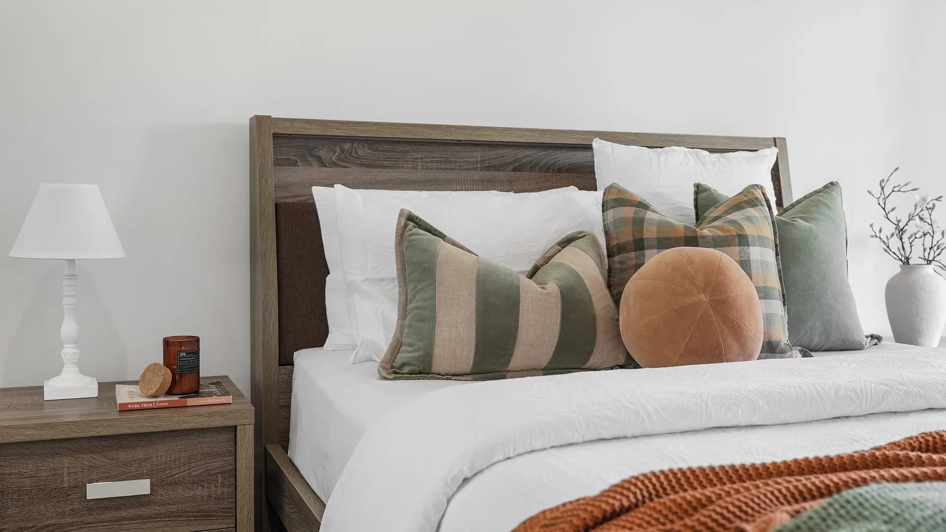 Bedroom styled with green and tan cushions and a timber bedhead at Chardonnay Drive, Moama