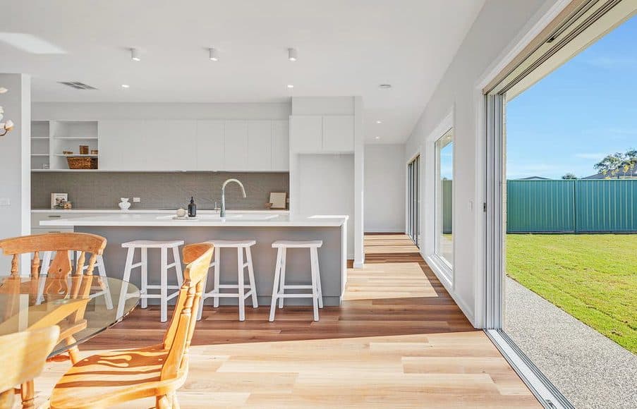 Kitchen and dining opening onto the back lawn through wide sliding doors, styled for sale by Wisteria & Oak