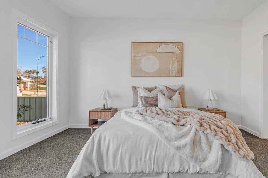 Main bedroom styled for sale by Wisteria & Oak, with layered white bedding, matching bedside lamps and a framed print