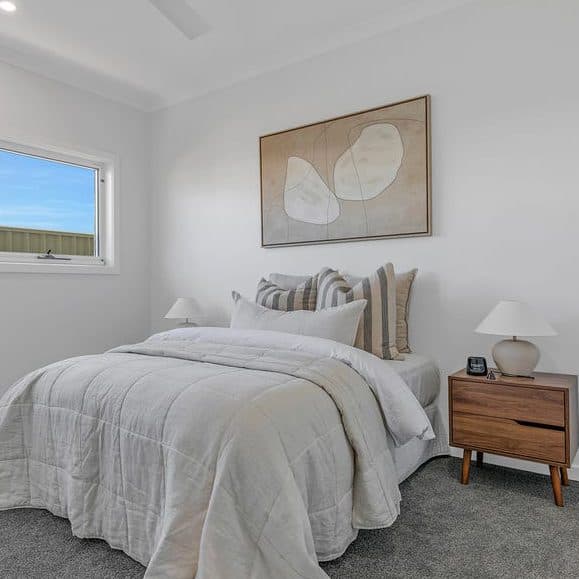 Bedroom styled for sale by Wisteria & Oak, with layered neutral bedding, a timber bedside table and framed artwork