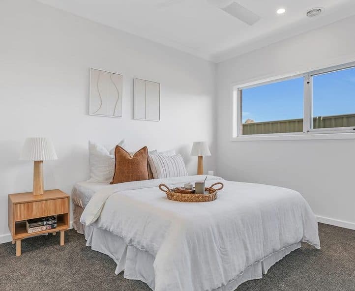 Guest bedroom styled for sale by Wisteria & Oak, with crisp white bedding, a rattan tray and matching bedside lamps
