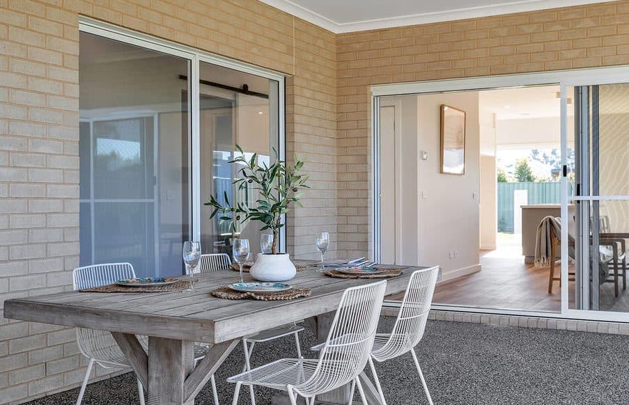 Outdoor dining table set under cover, looking back into the house, styled for sale by Wisteria & Oak