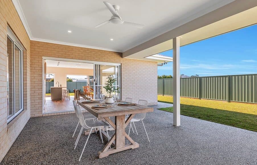 Covered alfresco styled by Wisteria & Oak, with a long timber table, white chairs and a ceiling fan looking out over the yard