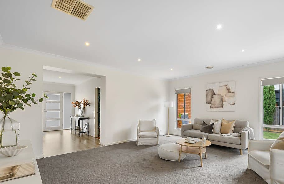 Living room styled for sale by Wisteria & Oak, with a linen sofa, framed artwork, a round timber coffee table and an outlook to the garden
