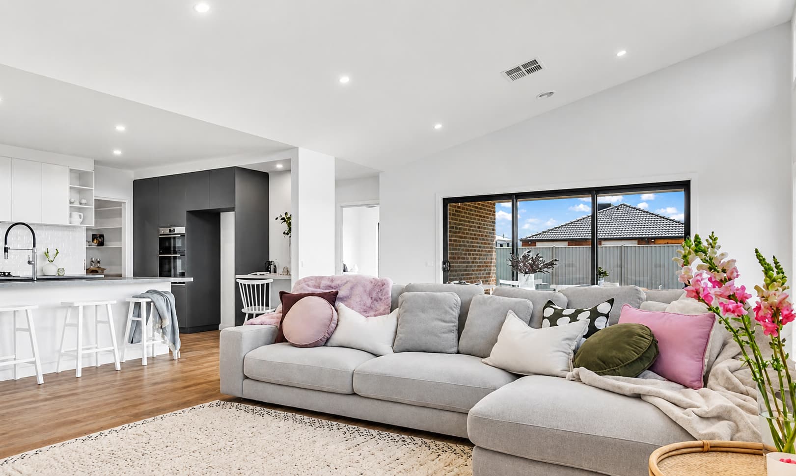 Open plan living and kitchen styled for sale by Wisteria & Oak, with linen sofas, a stone island bench and northern light