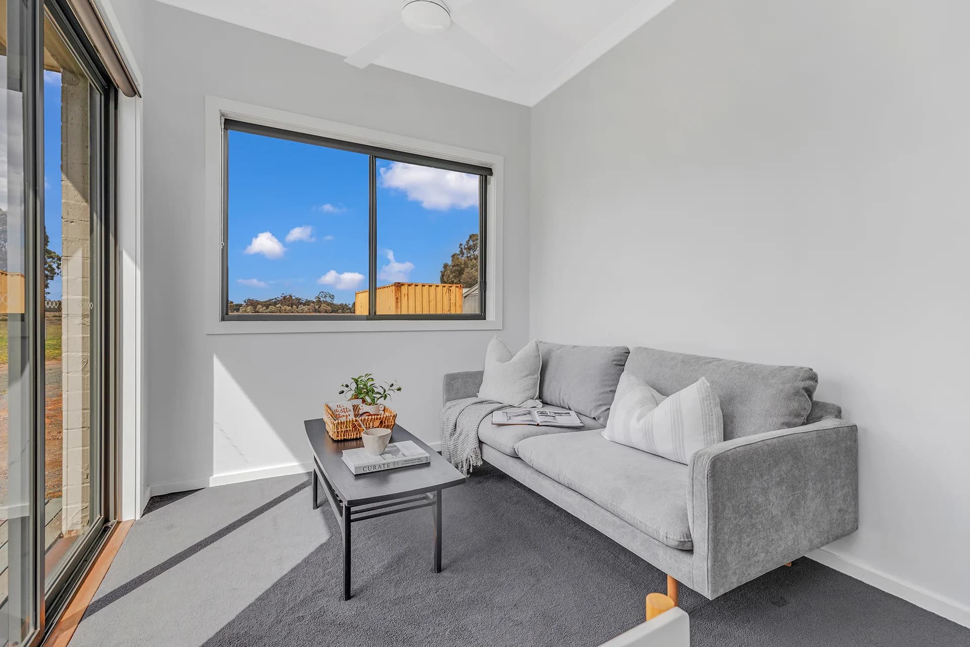 Living room with a grey sofa, low black coffee table and a window to the paddock at Perricoota Forest Road, Moama