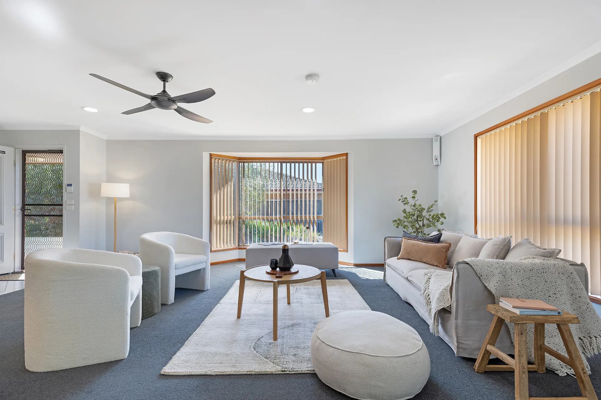 Living room with white tub chairs, a pale sofa and a round coffee table at Pevensey Place, Echuca