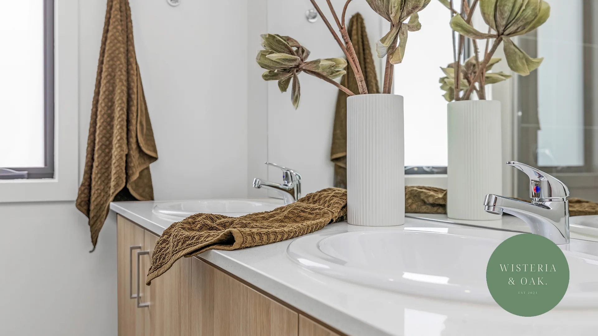 Bathroom vanity with a vase of dried stems and a folded towel at The Range, Moama